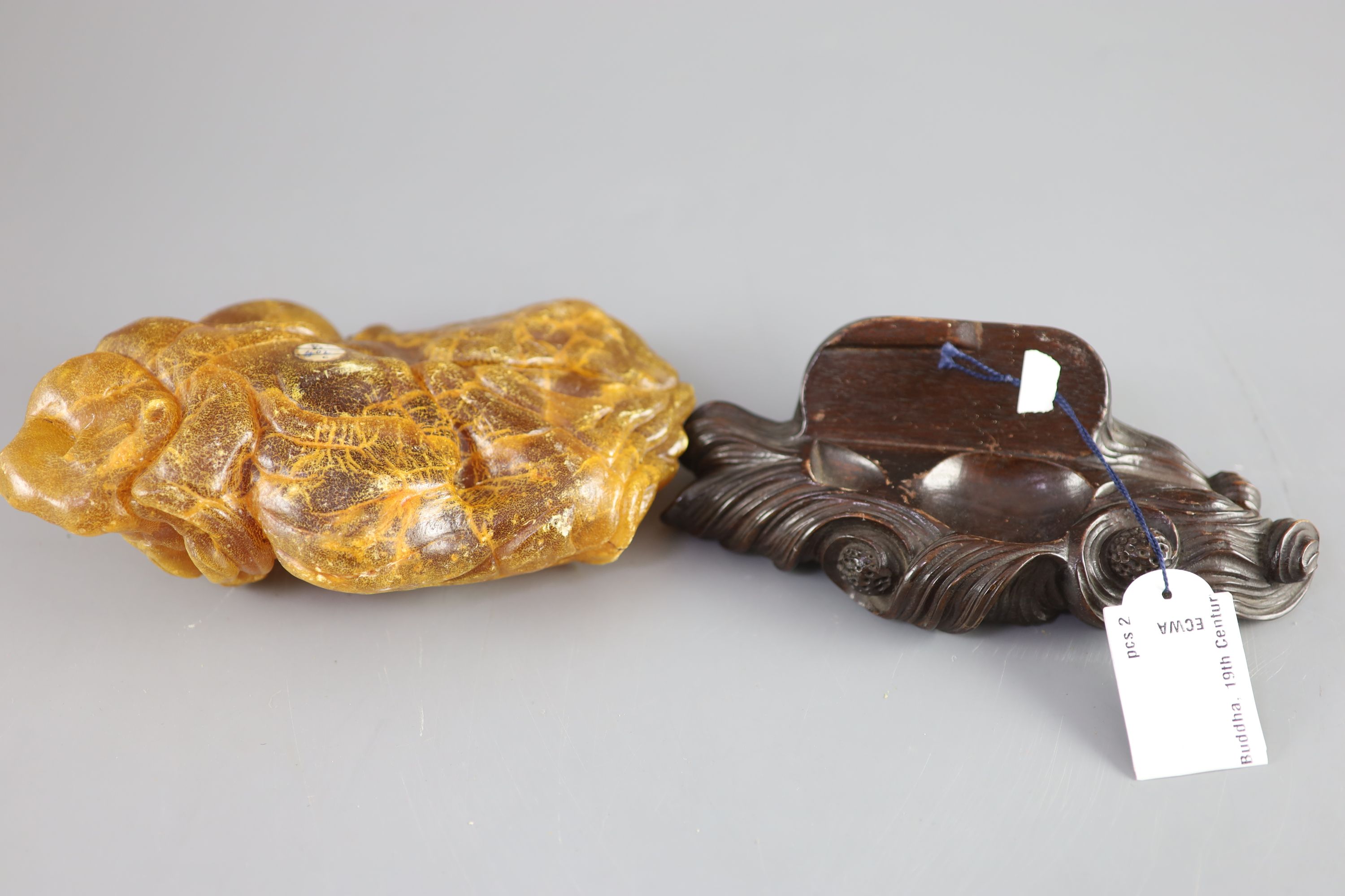 A Chinese amber figure of Buddha, 19th century, width 21.5cm